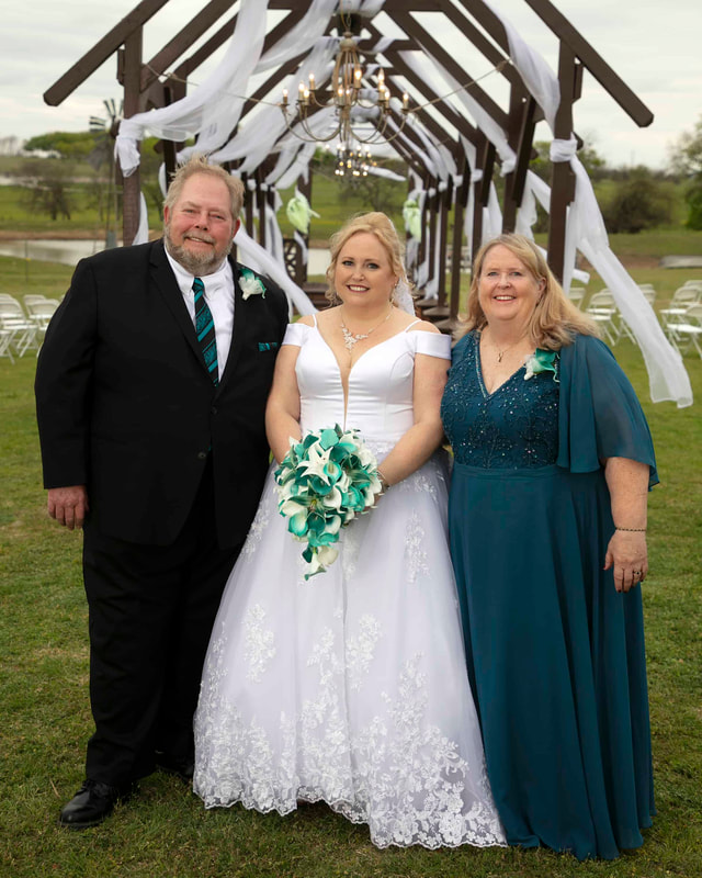 Bride holding flower bouquet with her father and mother